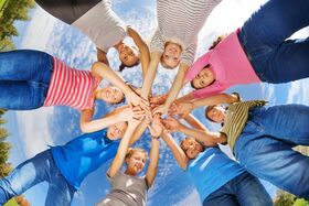 Kinder und Jugendliche strecken die Hände zusammen