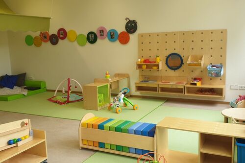 Gruppenraum in der Kita. Alles ist in hellen Grüntönen gehalten und es gibt viel Spielzeug aus Holz.