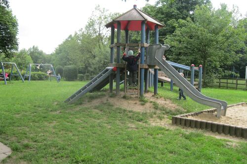 Spielturm mit Rutsche und Sandkasten auf der Wiese des Kindergartens Pepino Herbram