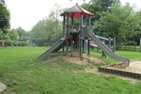 Spielturm mit Rutsche und Sandkasten auf der Wiese des Kindergartens Pepino Herbram